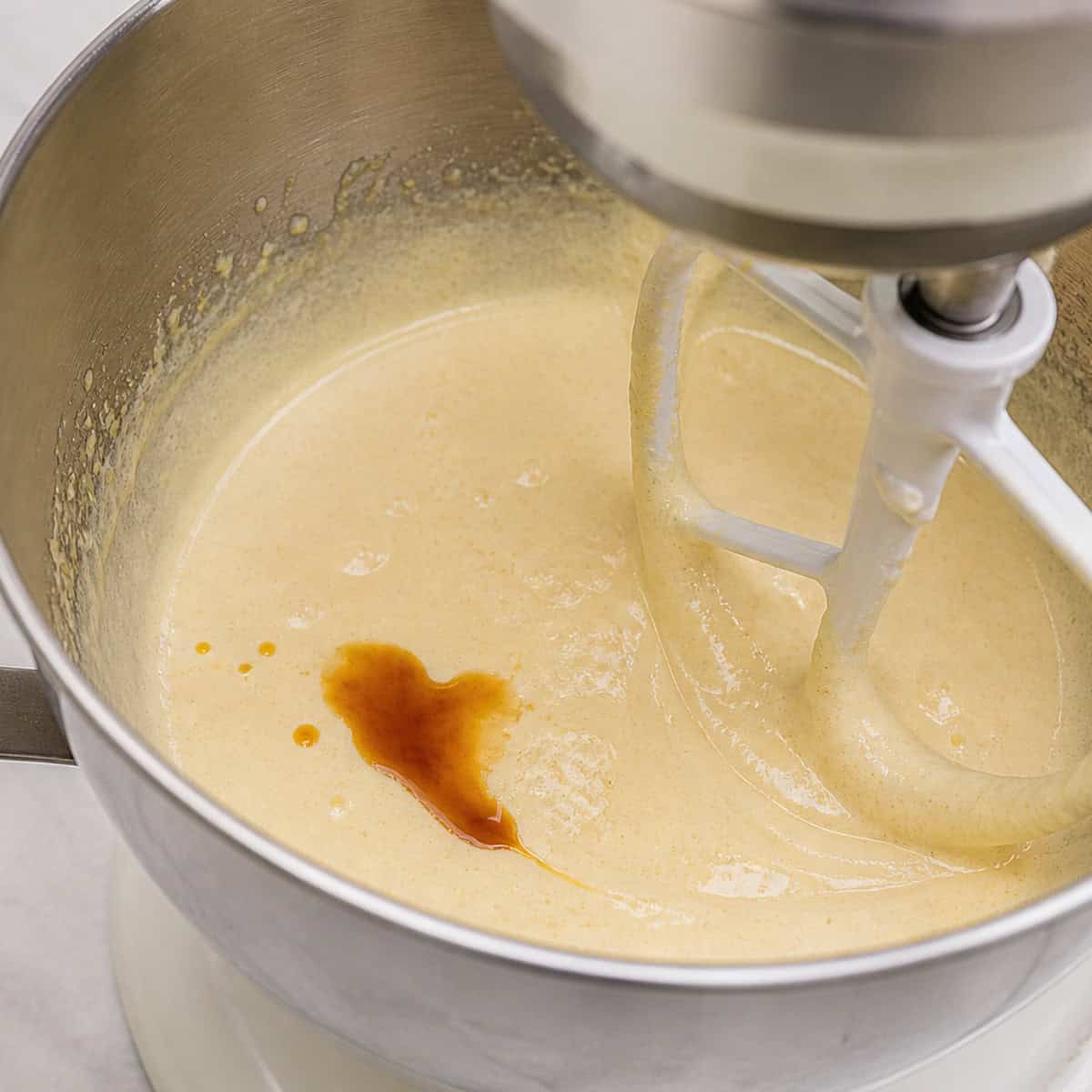 Beating eggs and butter with a splash of vanilla extract.