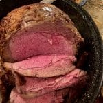 Slices of prime rib, medium-rare, in a roaster.