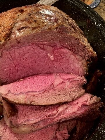 Slices of prime rib, medium-rare, in a roaster.