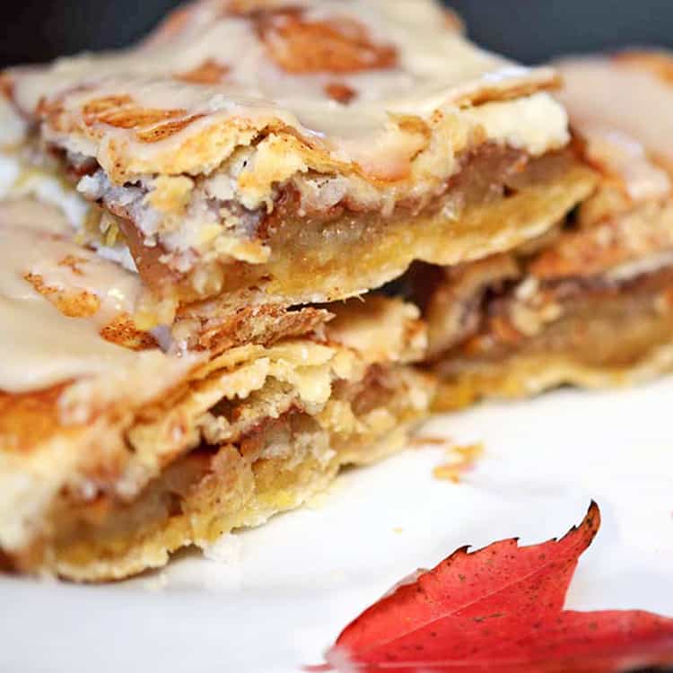 Cut glazed apple bars stacked on serving plate with fall leaf