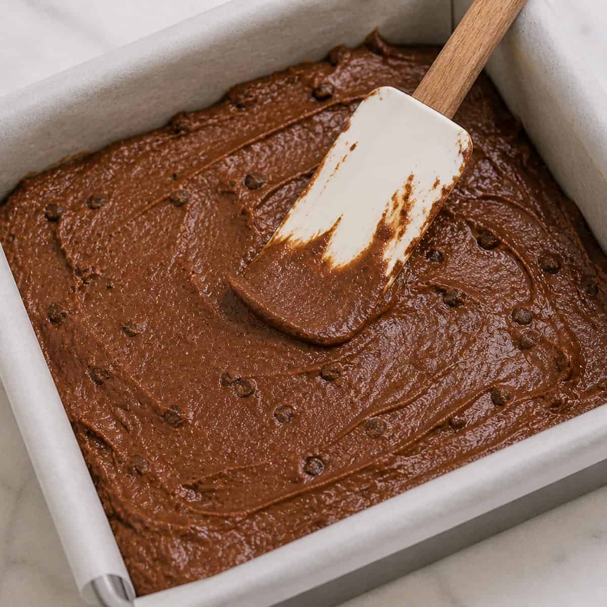 Spreading brownie batter in a baking pan.