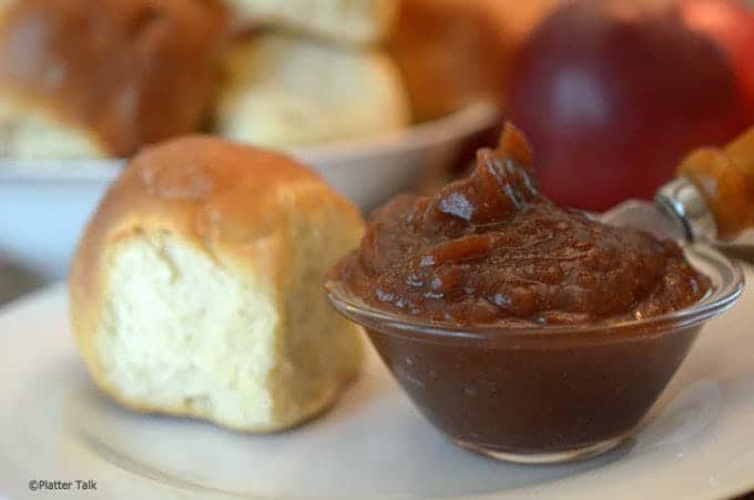 Custard dish of apple butter with roll on plate, rolls in background