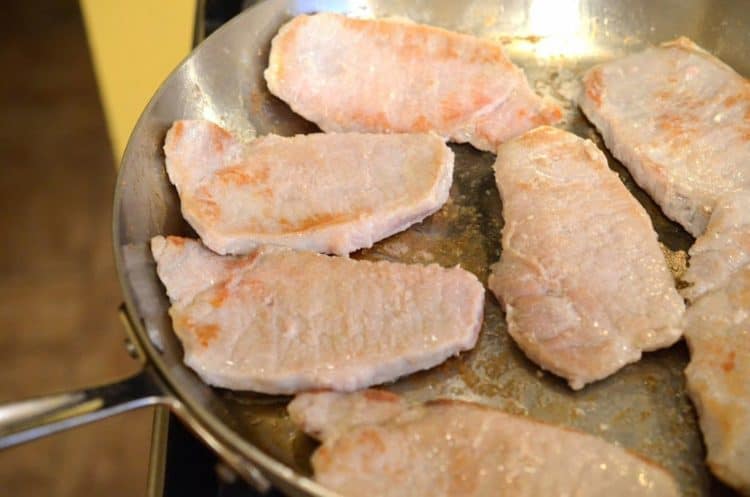 Searing boneless pork cutlets in a skillet.