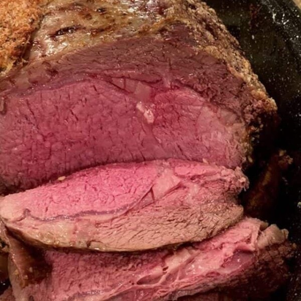 Slices of prime rib, medium-rare, in a roaster.