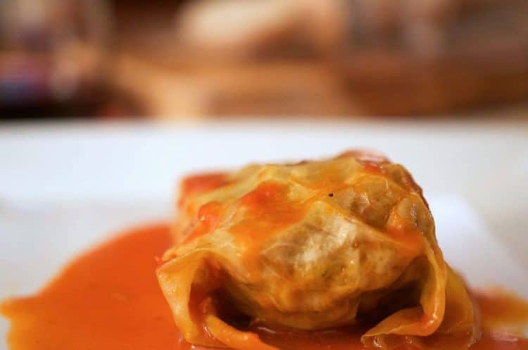 A close up of sauced cabbage roll on plate