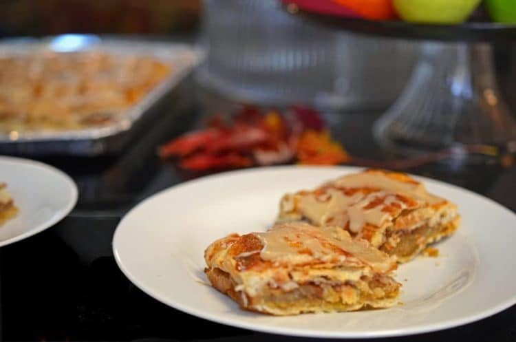 Angled servings of glazed apple dessert bar on plate, Autumn leaves in background