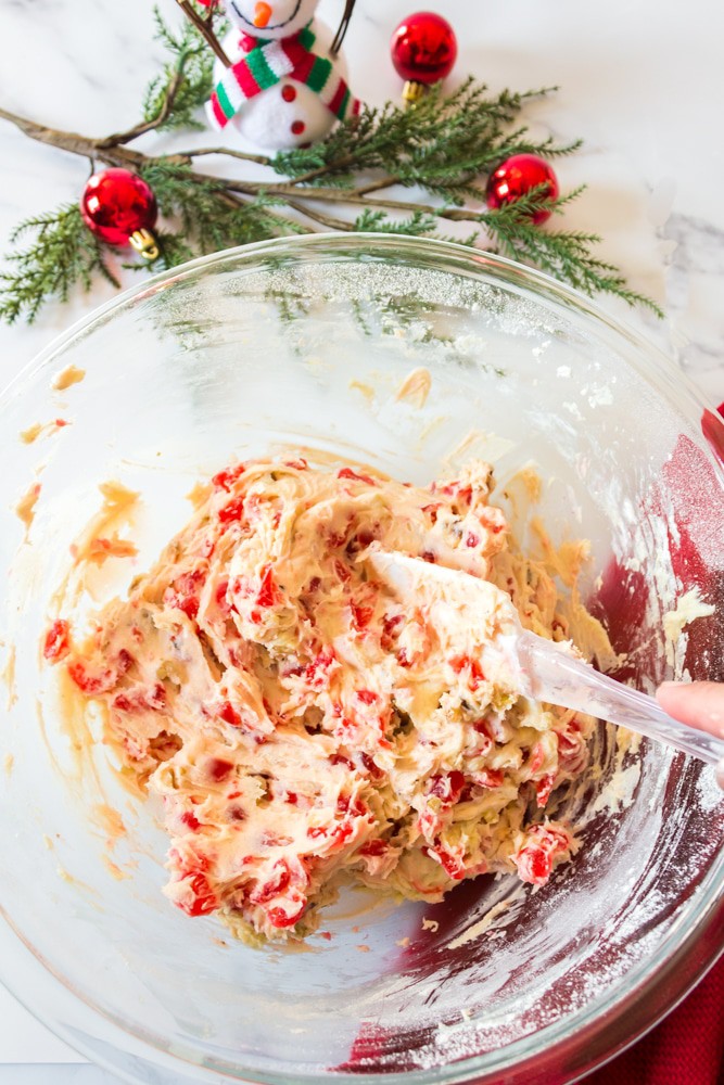 Using a spatula to stir cookie batter in a glass mixing bowl.