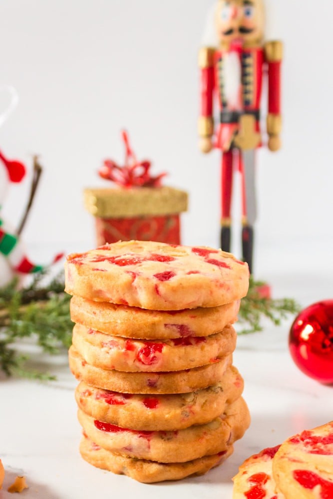 Stack of holiday cookies made with candied cherries.