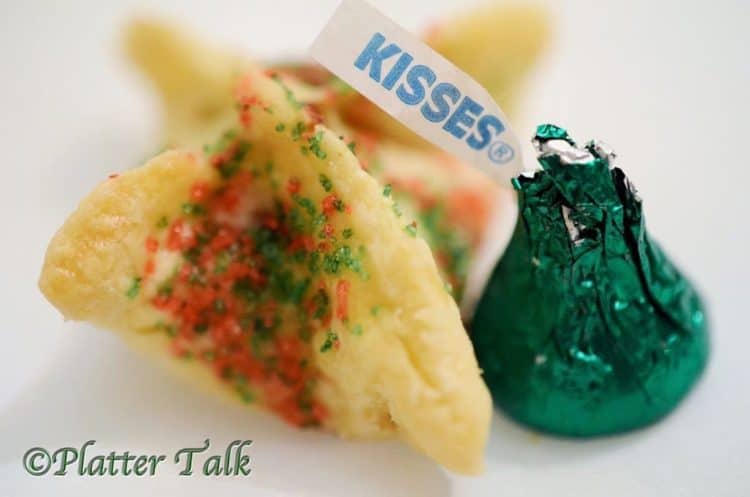 A Chrstmas-wrapped green Hershey kiss next to a holiday cookie.