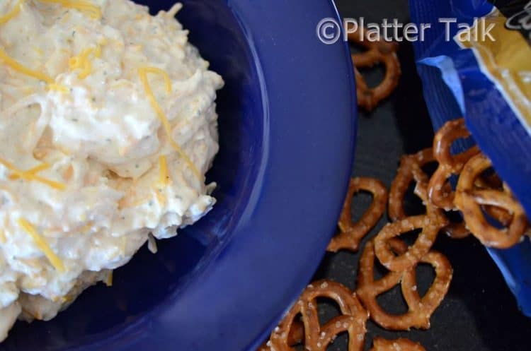 A bowl of dip with pretzels.