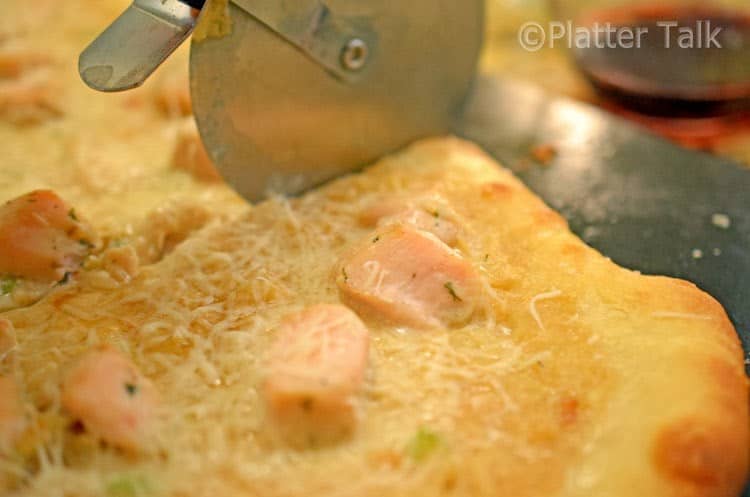A close up of a person cutting a slice of pizza