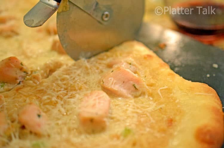 A close up of a person cutting a slice of pizza 