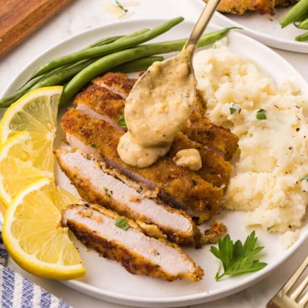 Adding sauce to a cut-up pork chop.