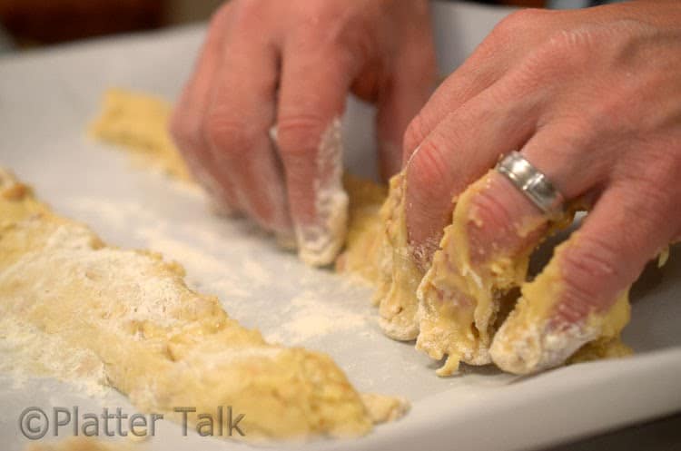 A close up of a person forming biscotti on a pan