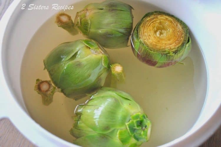 a bowl of artichokes soaking in water