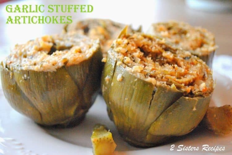 four garlic stuffed artichokes on a plate