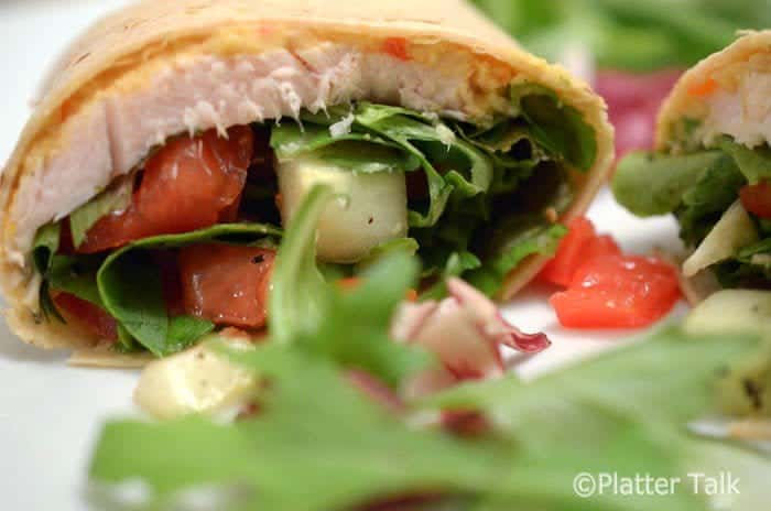 A close up of a wrap on a plate with turkey.