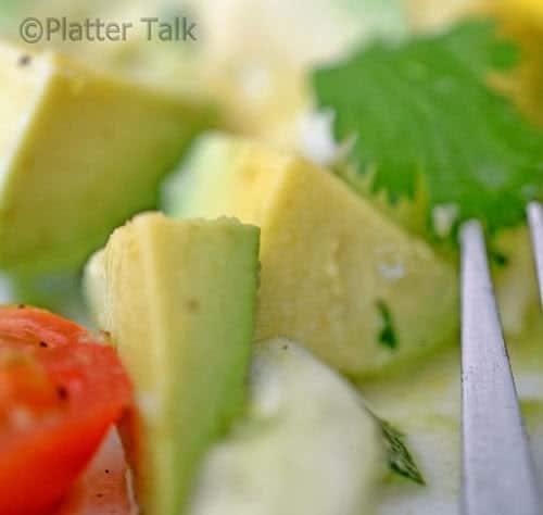 Close up diced avocado, cuke, tomato and cilantro 