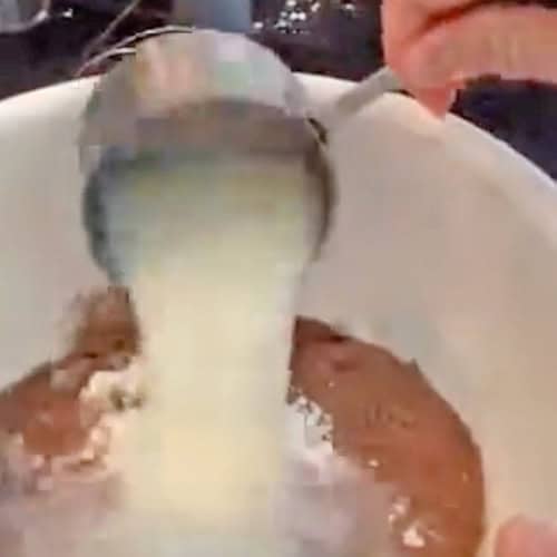 Adding milk to a mixing bowl with instant pudding mix.
