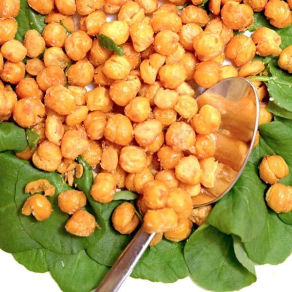 A dish of baked chickpeas on a bed of lettuce.