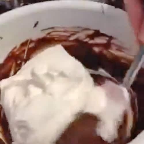 Folding cool whip into a mixing bowl of chocolate instant pudding.