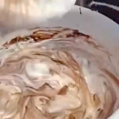 A mixing bowl with chocolate pudding and cool whip frosting.
