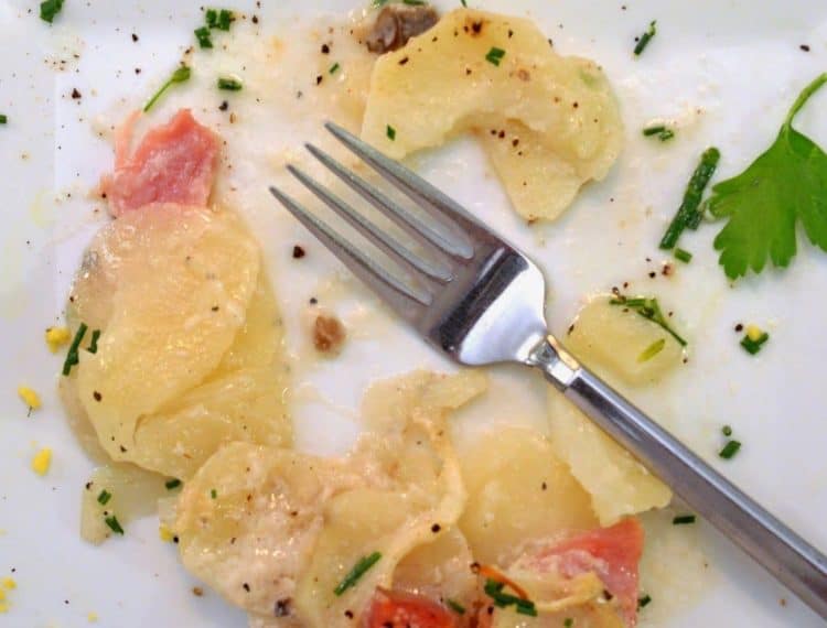 A close-up of a plate of food with a fork, with Potato and Ham.