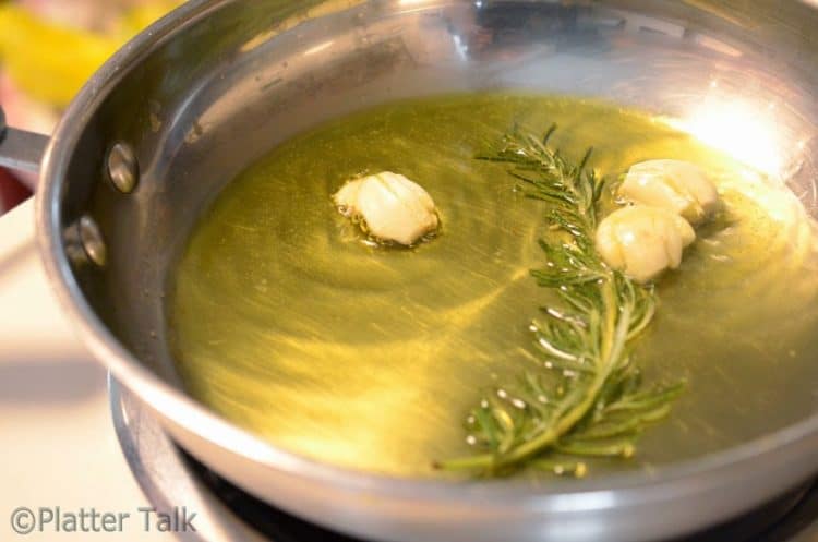 a pan with oil, garlic and herbs