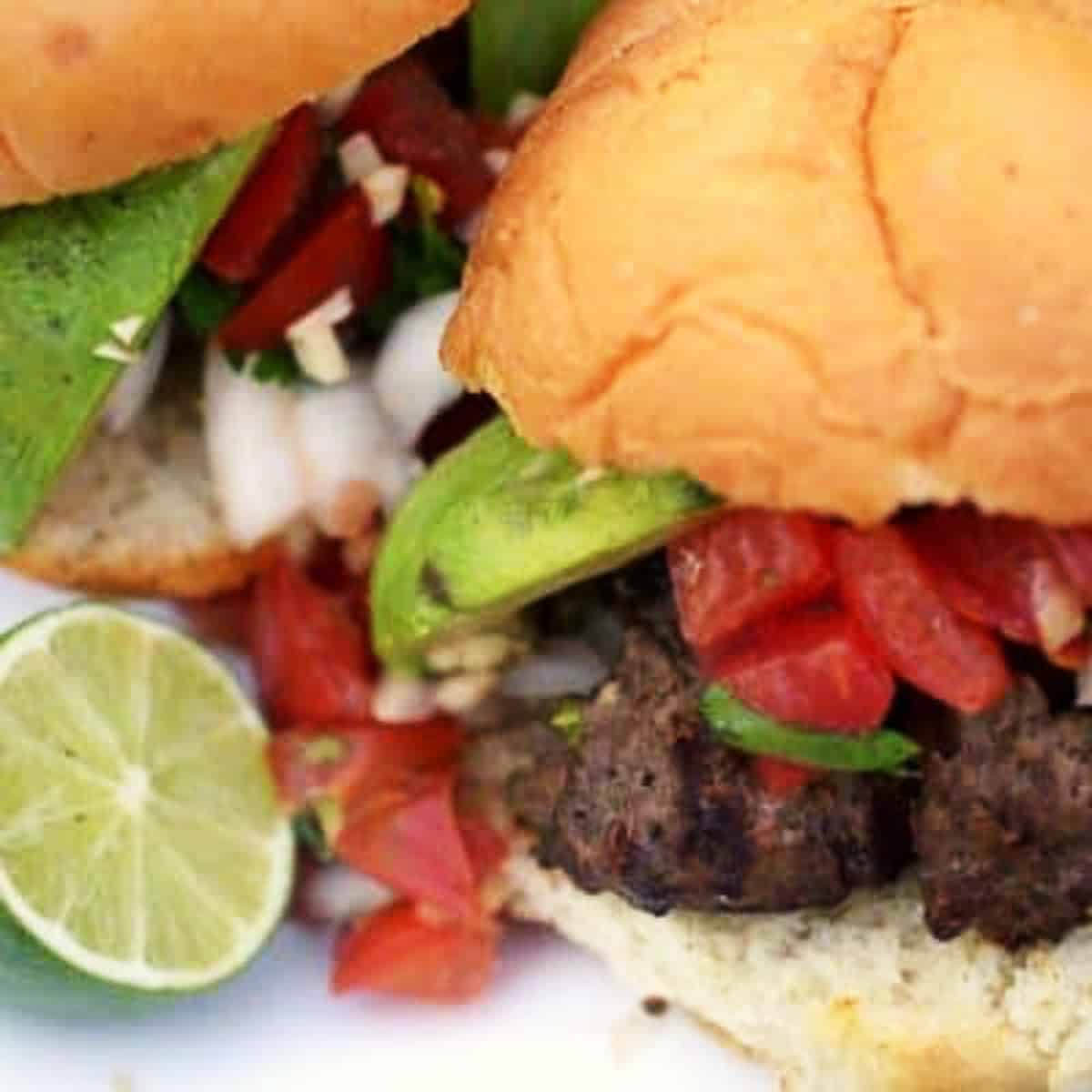 Close up of a burger on a bun with avocado and lime.