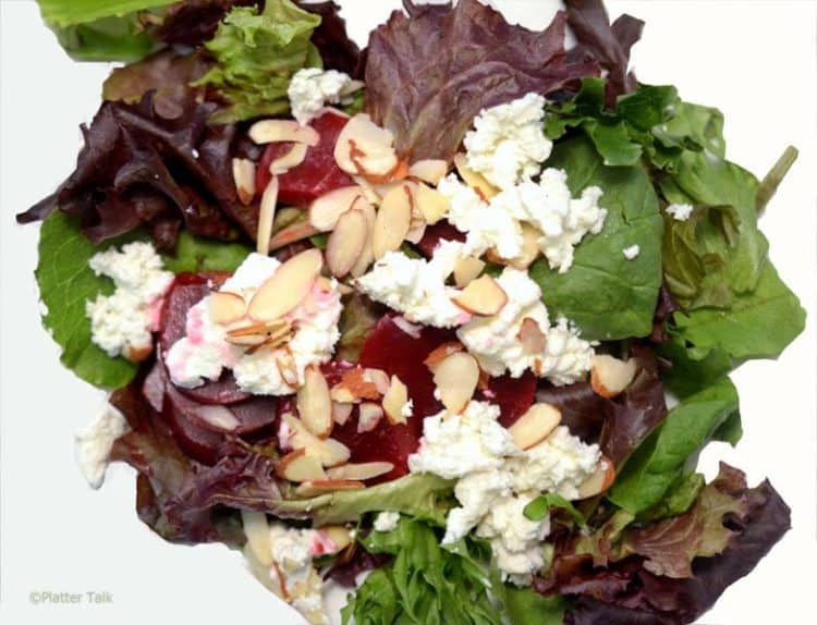 A plate of salad with beets and goat cheese.