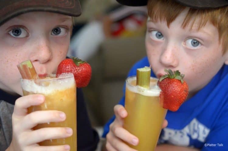 2 adorable boys close up, both drinking garnished glassed of slush