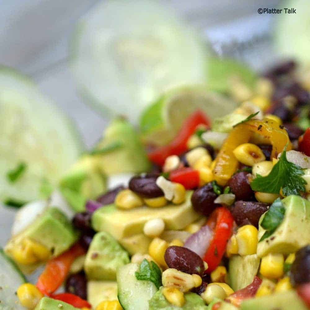 Corn salsa in a bowl with cucumber chips.