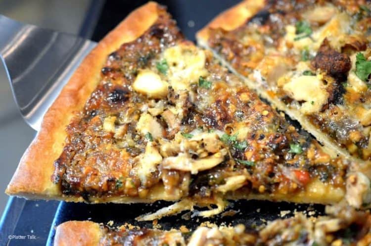 A close up of a slice of thai chicken pizza
