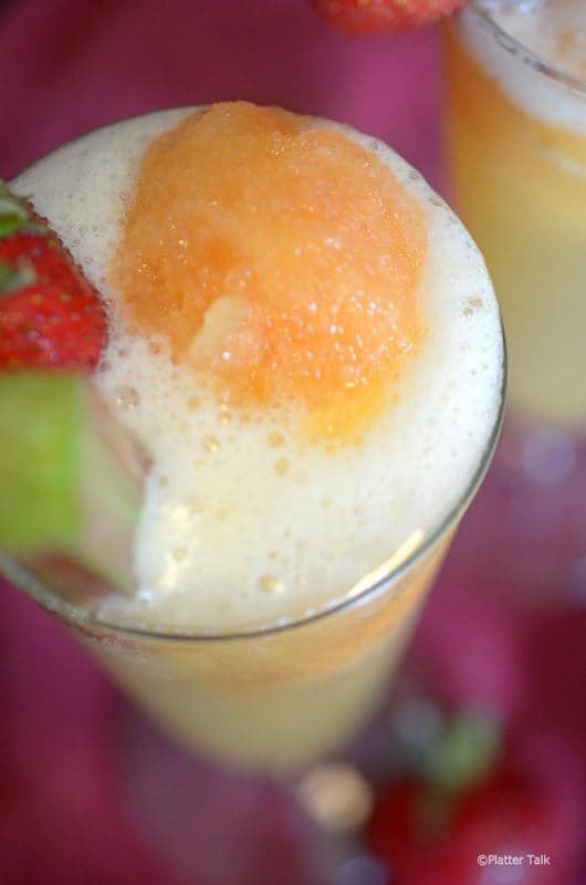 A close up of a glass of rhubarb slush garnished with fruit