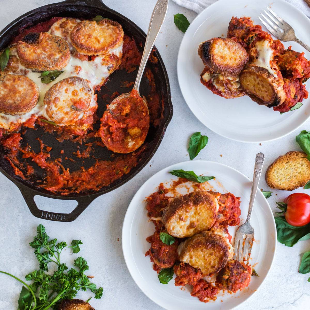 A skillet and two plates of meatball sub casserole