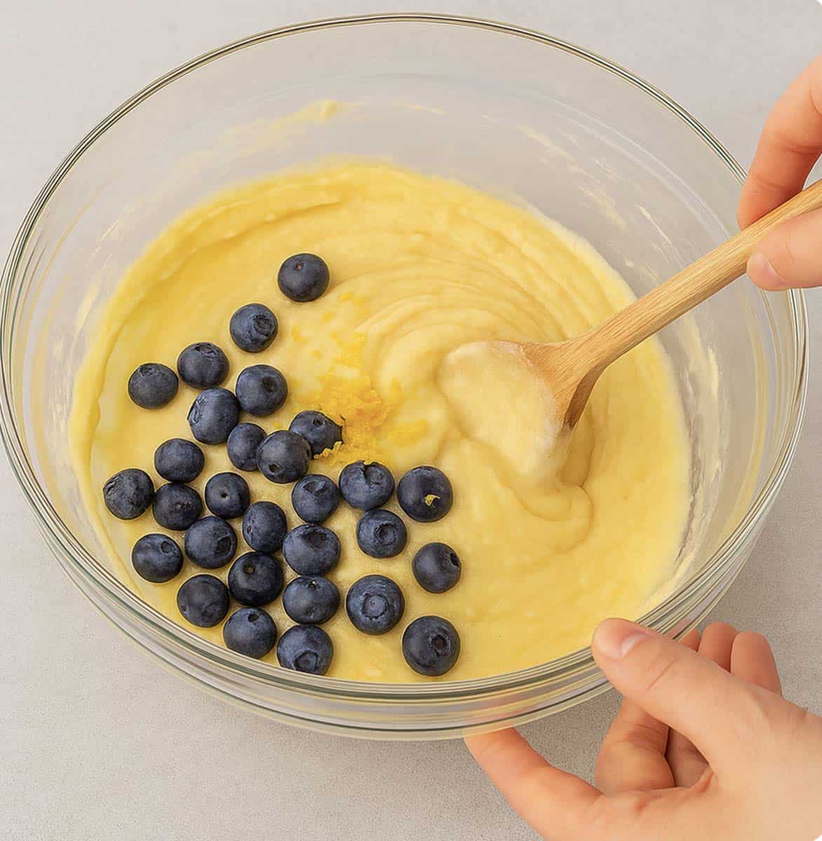 Folding blueberries into a mixing bowl.