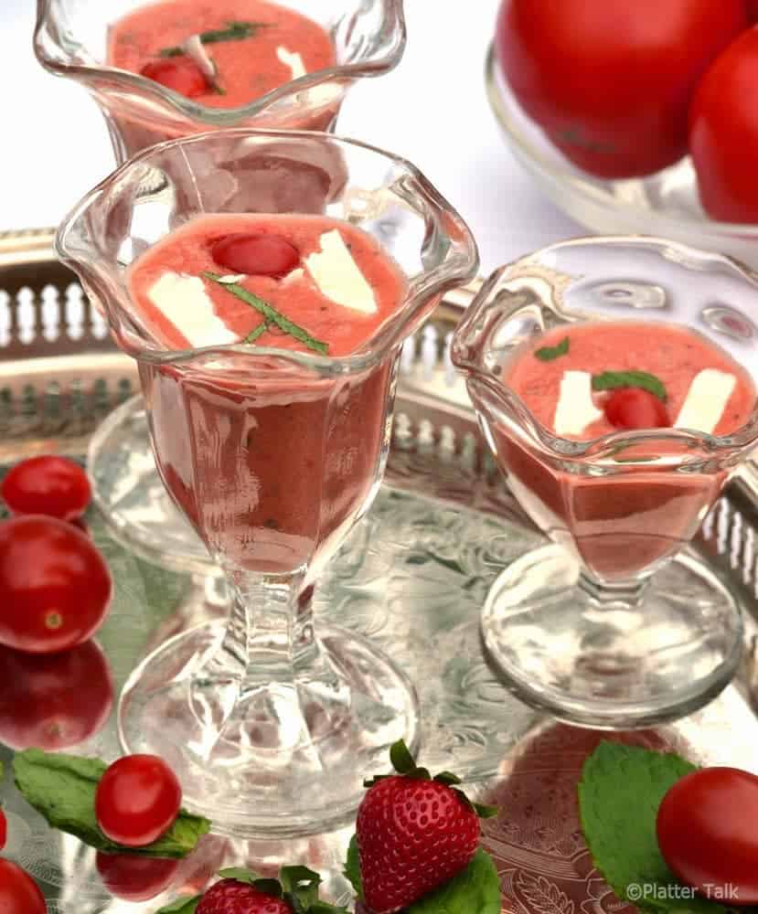 A group of glass bottles on a table filled with Gazpacho.