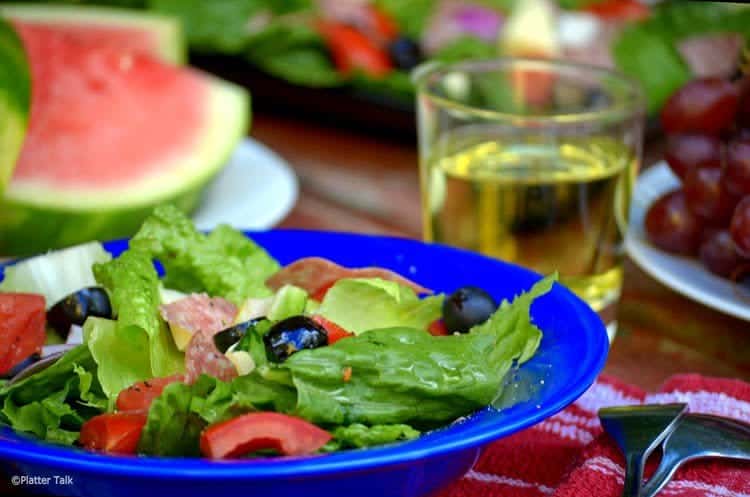 A bowl of salad with a glass of lemonade.