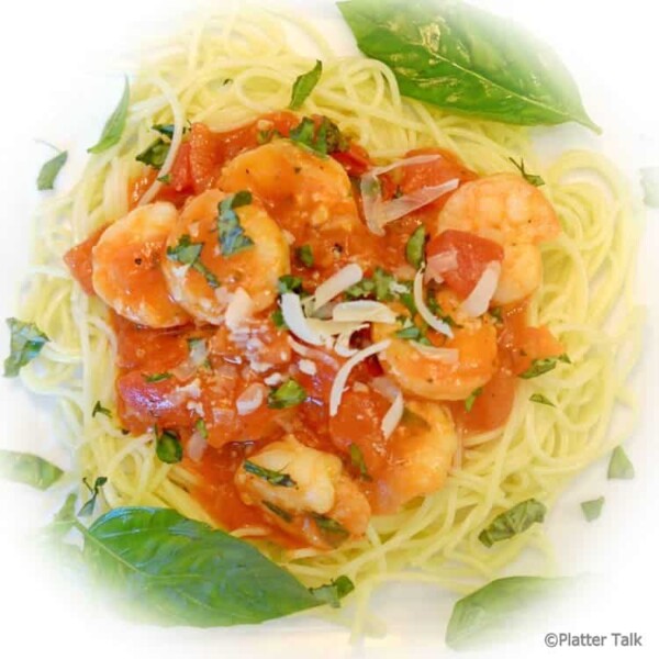 a plate of garlic basil shrimp with pasta.