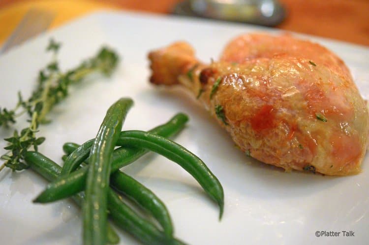 Dinner plate with chicken drumstick and green beans.