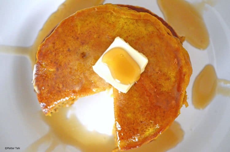 A pancake with a wedge cut out and butter and syrup on top