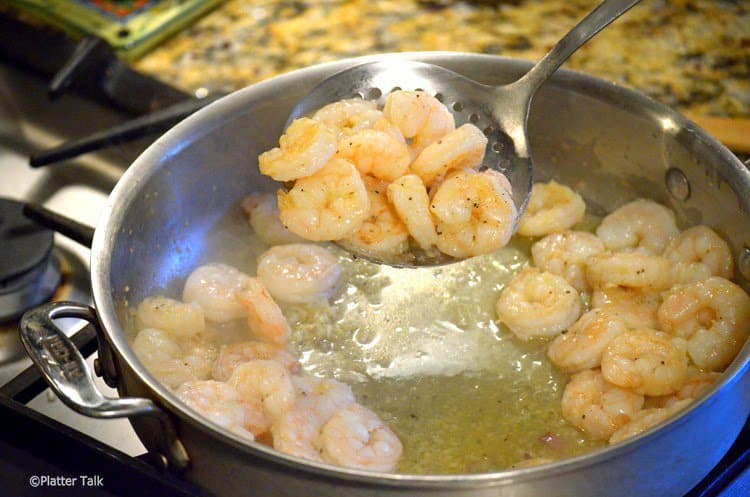 A person frying shrimp in a pan.