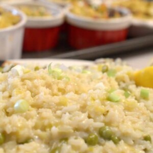 A close up of risotto with tray of  ramkins in background on sheet tray