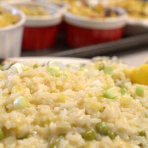 A close up of risotto with tray of ramkins in background on sheet tray