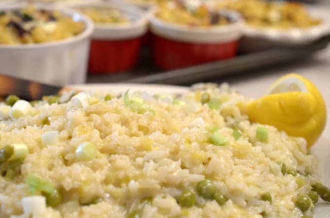 A close up of risotto with tray of ramkins in background on sheet tray