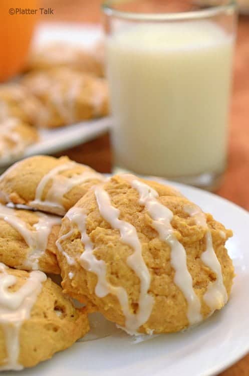 Plate of pumpkin cookies with a tall glass of milk.