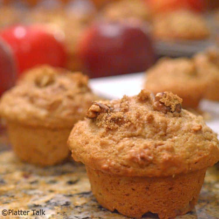 A group of muffins and some apples.