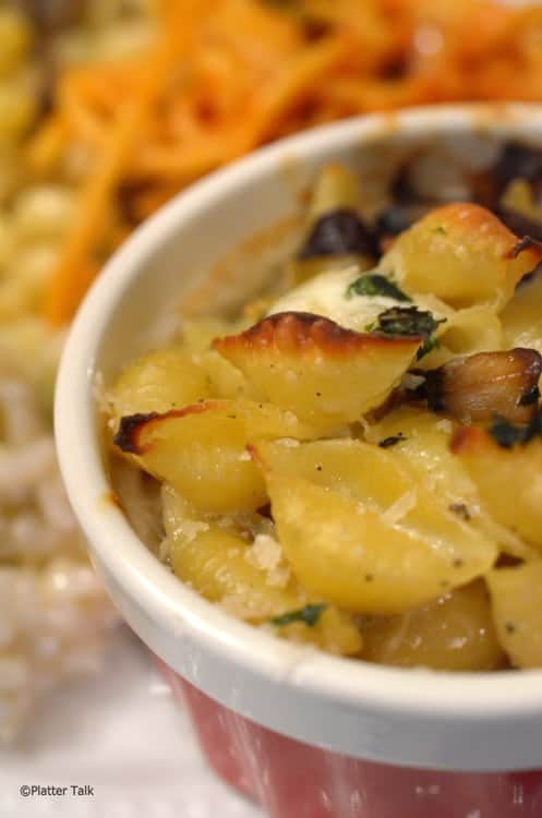 A close-up of a bowl of baked shells with sauce.