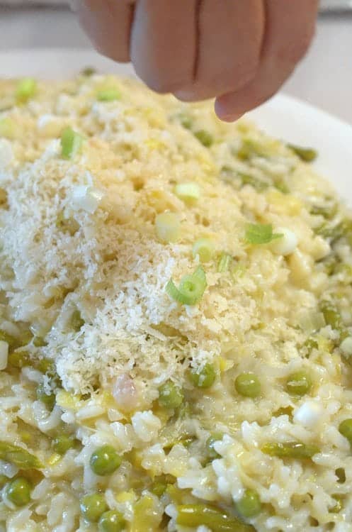 Risotto with someone delivering grated cheese to to of dish