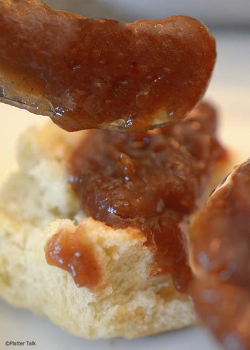 spreading apple butter on a dinner roll.